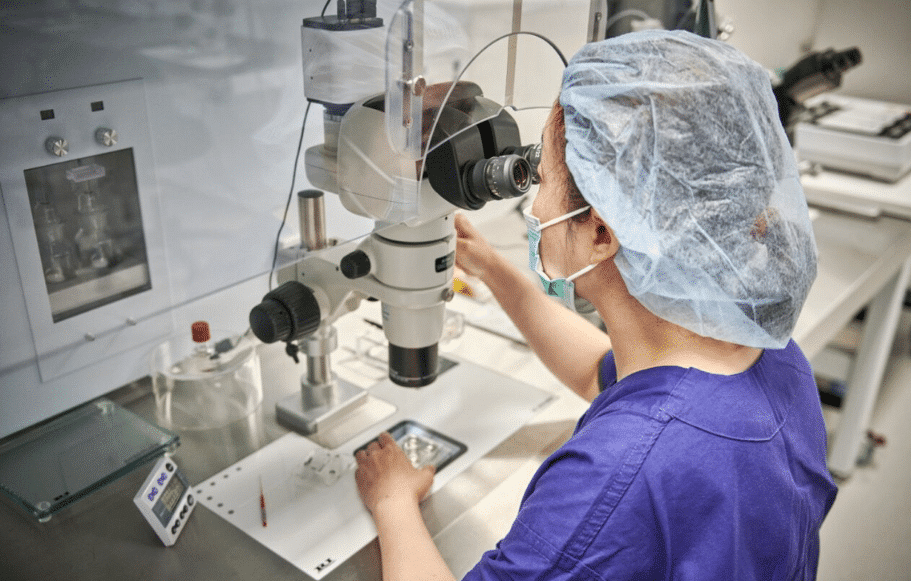 Scientists standing at microscope talking to each other